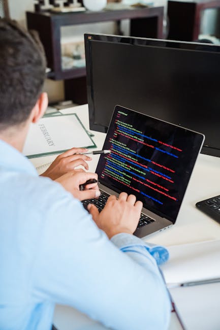 A close-up view of a computer screen displaying a colorful, blurred code editor with lines of programming code in various colors, including yellow, pink, green, blue, and white, indicative of software